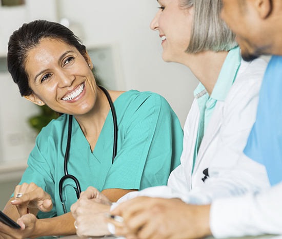 Group of doctors smiling and looking at a mobile device.